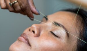 closeup photography of woman's eyebrow being threaded